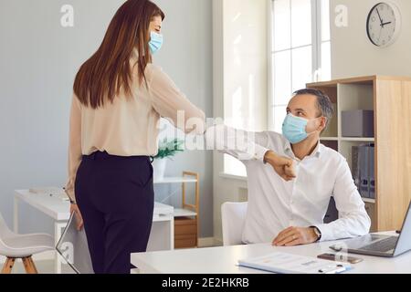 Kollegen in Gesichtsschutz Masken stoßen Ellbogen als Alternative Zum üblichen Händedruck Stockfoto