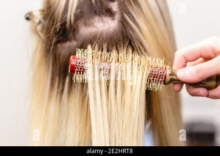 Haarverlängerungen Korrektur Verfahren. Friseur macht Haarverlängerungen zu blonden Haar Dame in einem Schönheitssalon Stockfoto