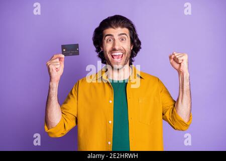 Foto-Porträt des feiernden Mann hält Plastikkarte in einem Hand isoliert auf lebhaft violettem Hintergrund Stockfoto