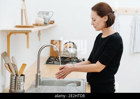 Mädchen in schwarzen Kleidern wäscht ihre Hände im Waschbecken Stockfoto