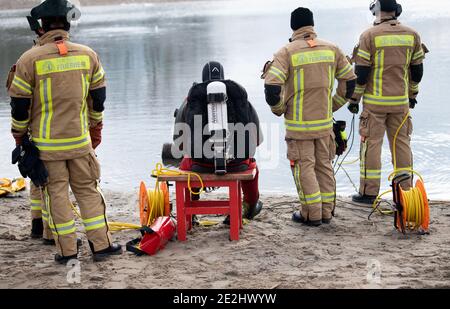 Berlin, Deutschland. Januar 2021. Mitglieder der Berliner Feuerwehr sind am Ufer des Habermann-Sees. Trotz der winterlichen Kälte haben Taucher der Berliner Feuerwehr ein versunkenes Auto aus einem See geholt. Hobbytaucher hatten das Autowrack am Habermannsee im Kreis Kaulsdorf entdeckt. Quelle: Paul Zinken/dpa-Zentralbild/dpa/Alamy Live News Stockfoto