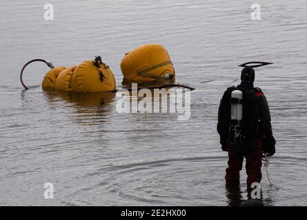 Berlin, Deutschland. Januar 2021. Ein Taucher der Berliner Feuerwehr schaut auf ein Luftkissen im Habermannsee. Trotz der winterlichen Kälte haben Taucher der Berliner Feuerwehr ein versunkenes Auto aus einem See geholt. Hobbytaucher hatten das Autowrack am Habermannsee im Kreis Kaulsdorf entdeckt. Quelle: Paul Zinken/dpa-Zentralbild/dpa/Alamy Live News Stockfoto