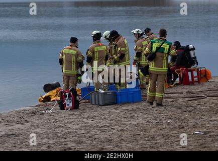 Berlin, Deutschland. Januar 2021. Mitglieder der Berliner Feuerwehr stehen am Ufer des Habermann-Sees. Trotz der winterlichen Kälte haben Taucher der Berliner Feuerwehr ein versunkenes Auto aus einem See geholt. Hobbytaucher hatten das Wrackauto am Habermannsee im Kreis Kaulsdorf entdeckt. Quelle: Paul Zinken/dpa-Zentralbild/dpa/Alamy Live News Stockfoto