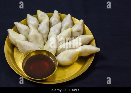 Köstliche bengalische Reismehl Kokosnussknödel während bengali indian Festival von makar sankranti serviert. Foto in schwarzem Hintergrund. Copy Space BA Stockfoto