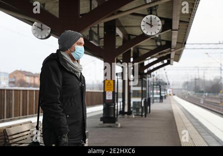 MOTALA, SCHWEDEN- 13. DEZEMBER 2020: Eine Person mit Gesichtsmaske wartet auf dem Bahnsteig in Östgötatrafiken Pendlerzug während dieser Corona-Zeiten. Stockfoto