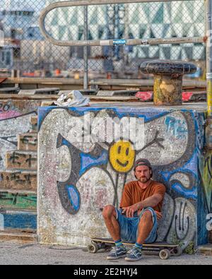 HELSINGBORG, SCHWEDEN - 08. AUGUST 2020: Ein erwachsener Mann hat eine Pause vom Fahren auf seinem Elektro-Skateboard im pixlapiren Skatepark in der Stadt. Stockfoto