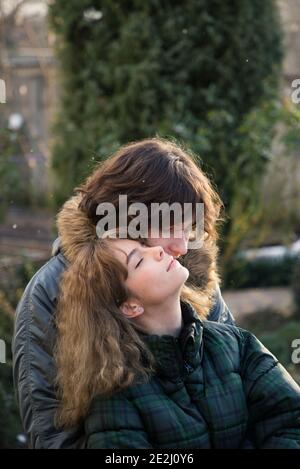 Verliebte junge Kerl und Teenager-Mädchen umarmen, genießen Sie den Moment. Draußen während der kalten Jahreszeit. Freudiges Treffen, zärtliche Gefühle. Valentinstag D Stockfoto