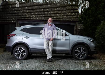 Lässig gekleideter älterer Mann mit seinem silbernen Auto. Stockfoto