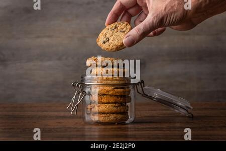 Hand greift nach einem Keks in einem Glas. Hafer und Rosinen hausgemachte Kekse Stockfoto