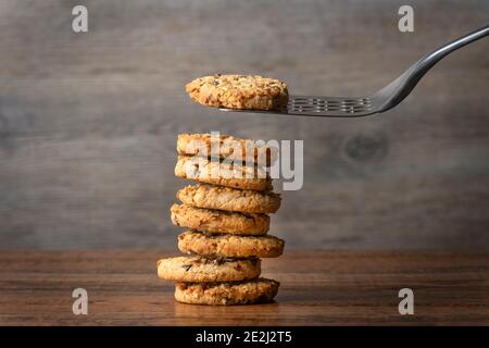 Vertikale Stapel von hausgemachten Hafer und Rosinen Cookies. Spatel, der einen aus dem Stapel nimmt. Stockfoto