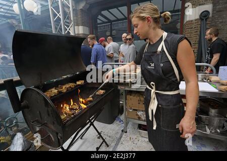 Meatopia in Tobacco Dock in London. Frau Grillen auf Grill Grill.BBQ gerösteten Knochenmark Stockfoto