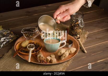 Frau gießt Masala-Tee mit Gewürzen, einem wärmenden Getränk aus Indien Stockfoto