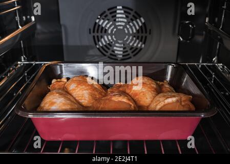 Hähnchenfleisch im Ofen in der Schale. Roher Drumstick im Ofen.Hähnchenschenkel im Ofen gebacken. Stockfoto