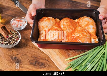 Ein Mädchen bereitet sich darauf vor, einen Drumstick im Ofen zu backen.Hähnchendrumstick in einem Backblech steht auf dem Tisch. Stockfoto