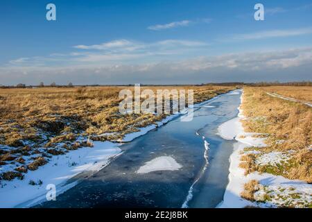 Gefrorener Fluss und trockene Wiesen, Blick auf den sonnigen Wintertag Stockfoto