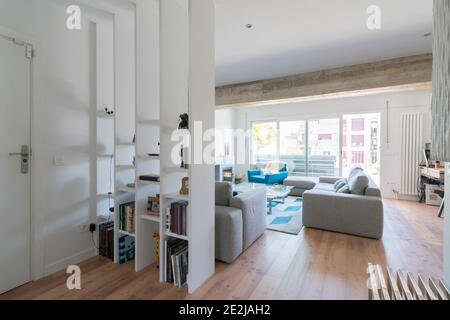 Modernes Wohnzimmer mit Kamin, grauen Sofas, einem grünen Stuhl und einer Glastür zur Terrasse. Stockfoto