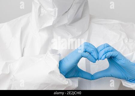 Arzt in einem biogefährlichen Schutzanzug und Schutzmaske gegen Coronavirus, SARS-Cov-2, Covid-19 Hände in einer Herzform in blau halten Stockfoto