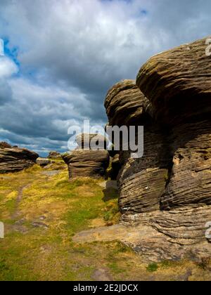 Stürme Wolken über den Felsformationen am Curbar Edge in The Peak District National Park Derbyshire England Großbritannien Stockfoto