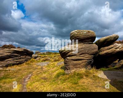 Stürme Wolken über den Felsformationen am Curbar Edge in The Peak District National Park Derbyshire England Großbritannien Stockfoto