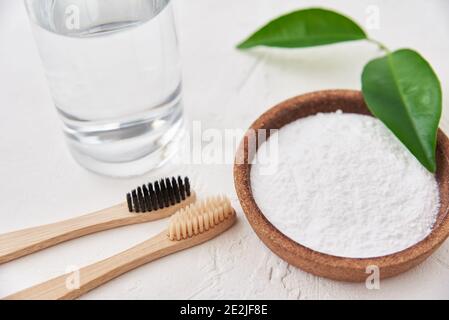 Bambus-Zahnbürsten, Backpulver und Glas Wasser auf weißem Hintergrund. Umweltfreundliche Zahnbürsten, Zero Waste Konzept Stockfoto