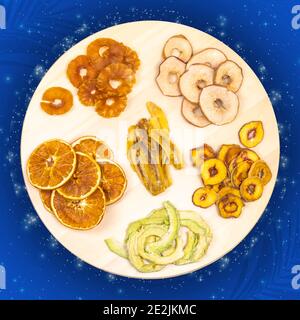 Tablett mit getrockneten Scheiben von Orange, Apfel, Ananas, Pfirsich und Banane auf einem blauen Raum Hintergrund. Fruchtchips. Gesunde Ernährung für guten Schlaf. Super Essen, Stockfoto