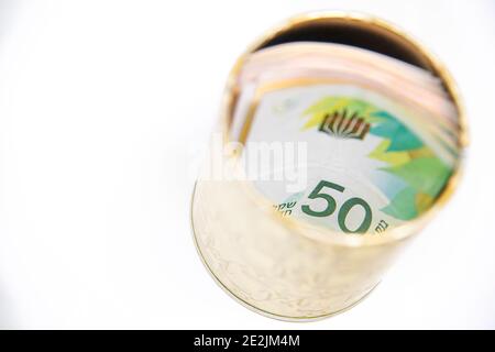 Metall Sparschwein mit New Israel Shekel Symbole für Geld zu sparen. Auf weißem Hintergrund mit NIS-Banknoten. Shekel in einer Blechdose speichern. Banknoten in einem spontanen Sparkonto halten. Konzept Foto in hoher Qualität Stockfoto