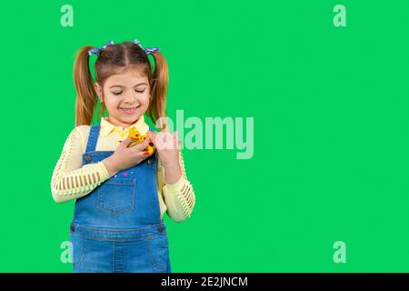 Das Mädchen lächelt lieblich und schaut auf ihre Eidechse zu Hause, die sie auf ihrer Brust hält und streichelt. Grüner Hintergrund. Leerer Seitenraum. Stockfoto