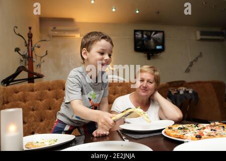 Großmutter mit ihrem Enkel, der Pizza in einem Restaurant isst Stockfoto