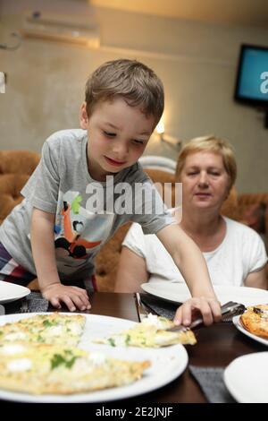Großmutter und ihr Enkel essen Pizza in einem Restaurant Stockfoto