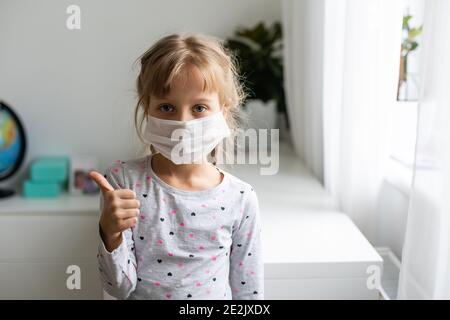 Covid-19 und pm2.5-Konzept für Luftverschmutzung. Kleines Mädchen trägt Maske zum Schutz pm2.5 und OK Fingerhände Geste für stoppen Corona Virus Ausbruch. Stockfoto