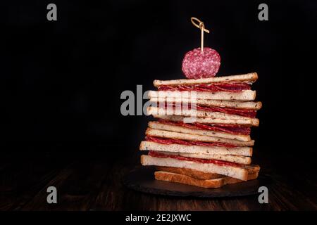 Heep von Sandwiches getoastetes Brot und Salami auf schwarz. Fast Food ungesunde Konzept. Speicherplatz kopieren Stockfoto