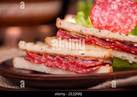 Heep von Sandwiches getoastetes Brot цшер Salami auf Holztisch. Fastfood ungesunde Konzept. Stockfoto