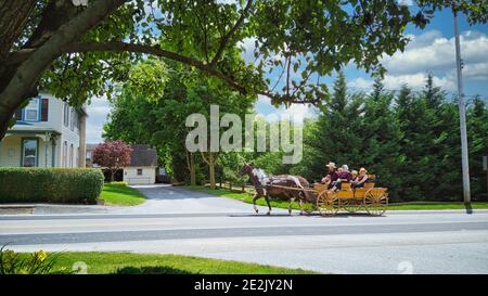 Gordonville, Pennsylvania, Juni 2020 - EINE große Amish Familie Reiten in einem offenen Pferd und Buggy auf einer Landstraße an einem Sommertag Stockfoto