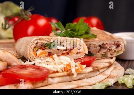Beliebte arabische türkische Fastfood Döner Shawarma Rolle mit Fleisch und Gemüse und Zutaten auf dunklem Hintergrund Stockfoto