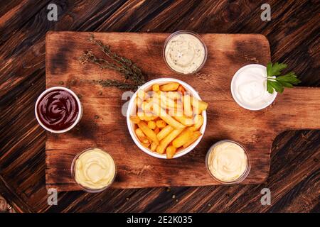 Pommes Frites Pommes Frites Kartoffel und Saucen auf Holzhintergrund. Draufsicht Stockfoto