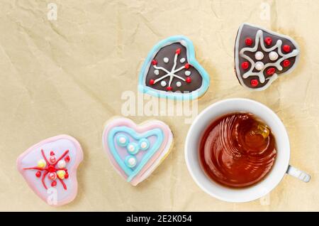 Heißer Tee in einer Tasse, mit herzförmigen Lebkuchen auf einem Hintergrund aus zerknittertem Papier. Valentinstag-Konzept, Draufsicht Stockfoto