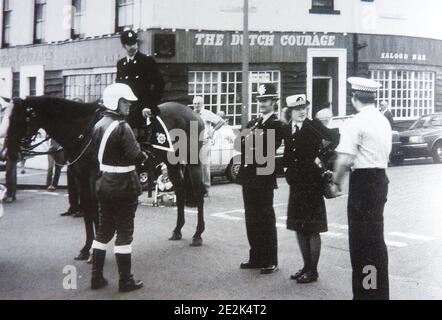 Eine etwa Ende der 1960er Jahre stattfindende Versammlung der britischen Polizei in Whitby, North Yorkshire's jährlicher Regatta, England, zeigt die verschiedenen Uniformen und Kopfbedeckungen, die von verschiedenen Dienststellen zu dieser Zeit getragen wurden. -- auf seinem Pferd montierter Polizist, Motorrad-Cop, Beat bobby (mit Helm), Polizist und Kader-Autofahrer (weißes Hemd) dahinter ist die ehemalige niederländische Courage Bar (jetzt nicht mehr vorhanden), die Teil des Royal Hotel auf Whitby's West Cliff war. Stockfoto