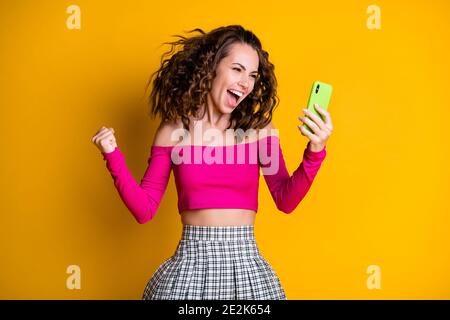 Foto von niedlichen Dame halten Telefon lockig Frisur verrückt offen Mund Triumph aufgeregt Lotterie gewinnen tragen rosa oben unbekleidete Schultern Minirock isoliert Stockfoto