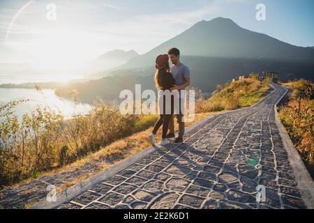 Junges Paar, das sich von Angesicht zu Angesicht mit Blick auf den See sieht Atitlan bei Sonnenaufgang - ein Paar, das sich verliebt lake ViewPoint in Guatemala Stockfoto