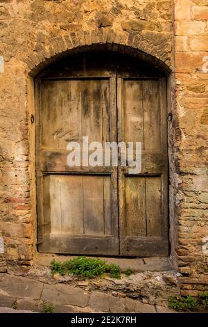 Eine alte Holztür in einem stillstehen Wohnhaus im Dorf Montalcino in der Provinz Siena, Toskana, Italien Stockfoto