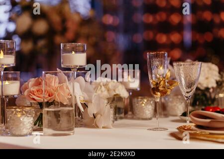 Dekorierte Tischeinstellung Hintergrund. Gläser, Kerzen in den Kerzenständern und Rosen. Bankett Stockfoto