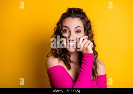 Foto-Porträt von goofy Mädchen machen Haar Schnurrbart lächelnd halten Mit handgetragenem rosa Crop-Top isoliert auf lebhaft gelb gefärbt Hintergrund Stockfoto