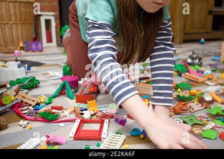 Junge Mädchen spielen mit playmobil auf Teppich Boden Stockfoto