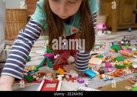 Junges Mädchen saß auf dem Boden spielend mit playmobil Stockfoto