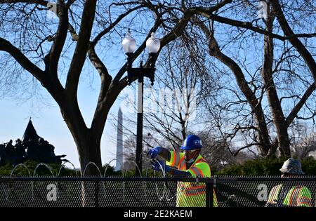 Washington, Usa. Januar 2021. Arbeiter installieren am Donnerstag, dem 14. Januar 2021, in Washington, DC, Rasierdraht auf einem 8-Fuß-Zaun, der das US-Kapitol umgibt, inmitten verstärkter Sicherheitsbemühungen während der Vorbereitungen für Joe Bidens Amtseinführung, die für den 20. Januar geplant ist. Foto von David Tulis/UPI Credit: UPI/Alamy Live News Stockfoto