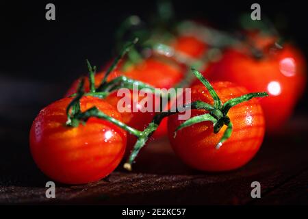 Helle rote Kirschtomaten auf dunklem Hintergrund. Gesunde Ernährung. Mit Schatten. Selektiver Fokus Stockfoto