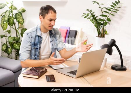 Fokussierter junger Geschäftsmann, der Videoanruf mit Kunden auf dem Laptop hält. Konzentrierter Millennial Mann in Brille, die Online-Unterricht Vorlesung Stockfoto