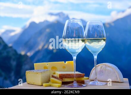 Schmackhafter Käse und Wein aus Savoyen in Frankreich, beaufort, abondance, emmental, Tomme und Reblochon de savoie Käse und ein Glas Weißwein serviert Stockfoto