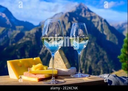Schmackhafter Käse und Wein aus Savoyen in Frankreich, beaufort, abondance, emmental, Tomme und Reblochon de savoie Käse und ein Glas Weißwein serviert Stockfoto