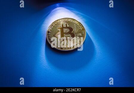 Krypto-Geld-Konzept. Spot Licht auf goldenen Bitcoin Metall Münze mit viel Kopieplatz auf blauem Hintergrund. Stockfoto